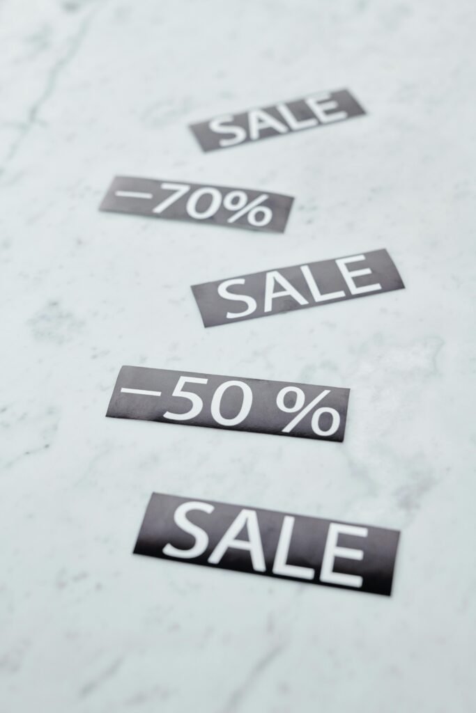 Minimalist image showing sale signs with discount percentages on a marble surface.